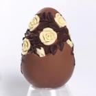 Uovo di Pasqua di cioccolato con rose decorate in rilievo poggiato su anello di cioccolato bianco 
